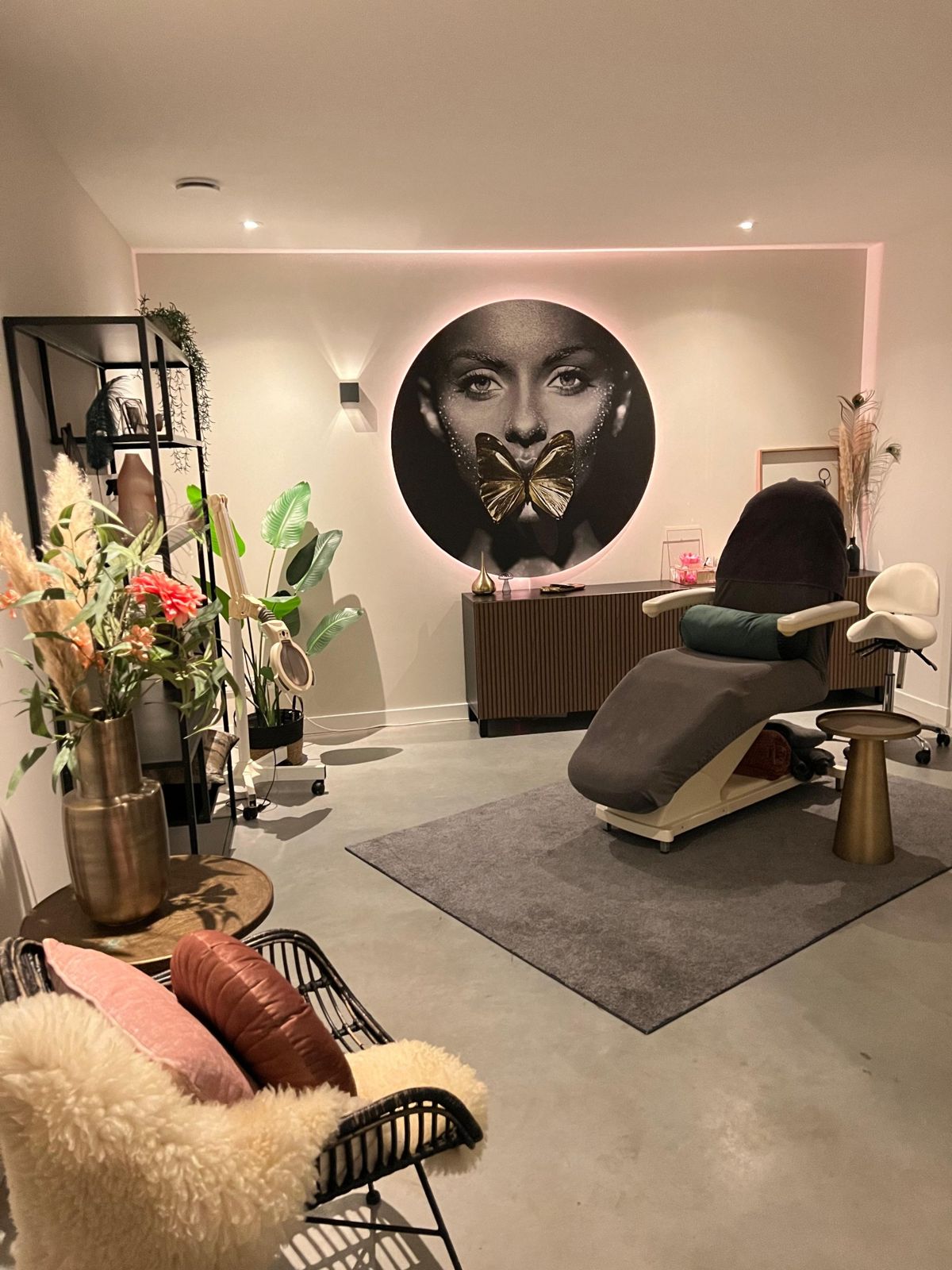 Behandelruimte van Evident Beauty met behandelstoel, warme verlichting en een groot rond portret aan de wand